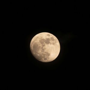 A detailed close-up of the full moon against a dark, clear night sky.