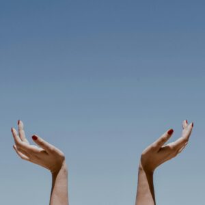 Uplifted hands against a clear blue sky in Apollo Bay, Australia, symbolizing freedom and joy.